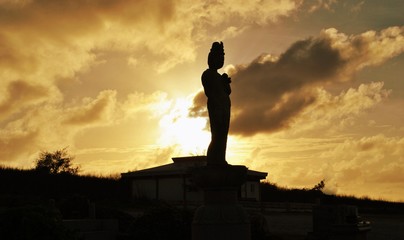 Silhouette of a statue at sunset, Banzai Cliff, Saipan  A statue at the memorial sites at Banzai Cliff is silhouetted by golden sunset skies