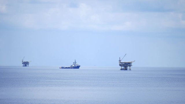 Small offshore platform and crew boat in the middle of the ocean 
