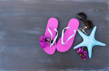 Summer beach fun - sandals with glasses and starfish on dark wooden background