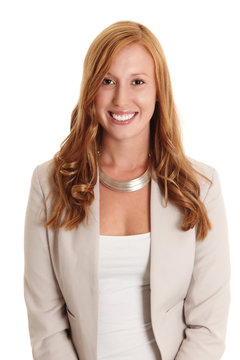 Attractive businesswoman wearing a bright blazer and white top, standing against a white background. Red hair and a big smile on her face.
