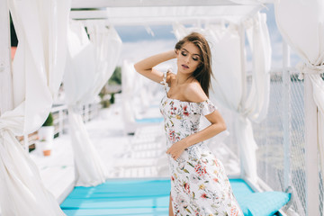 Fototapeta na wymiar Portrait of a beautiful woman in a dress posing on a white wooden beach of summer.