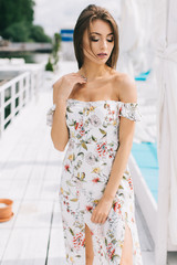 Fototapeta na wymiar Portrait of a beautiful woman in a dress posing on a white wooden beach of summer.