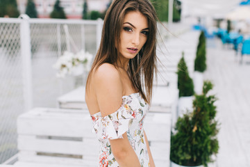 Portrait of a beautiful woman in a dress posing on a white wooden beach of summer.