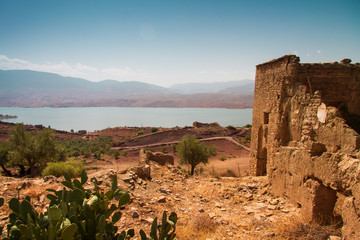 ruin of a kasbah with view of lake against sky in a sunny day - bine el ouidane - morocco