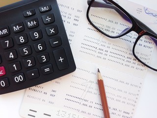 Business, finance, savings, banking or  loan concept : Pencil, calculator, eyeglasses  and savings account passbook or financial statement on white background