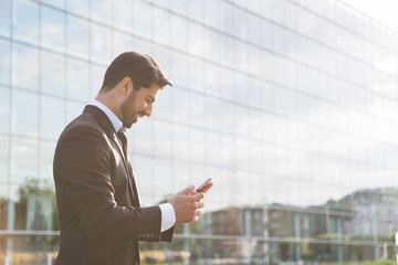 Successful businessman or worker standing in suit with cellphone