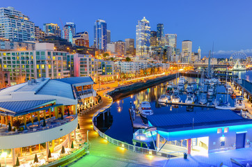 Beautiful view of Seattle waterfront and skyline at blue hour. Marina at pier 66, the great wheel (ferris wheel) can be seen in distance at far left corner. Travel and urban architecture background.