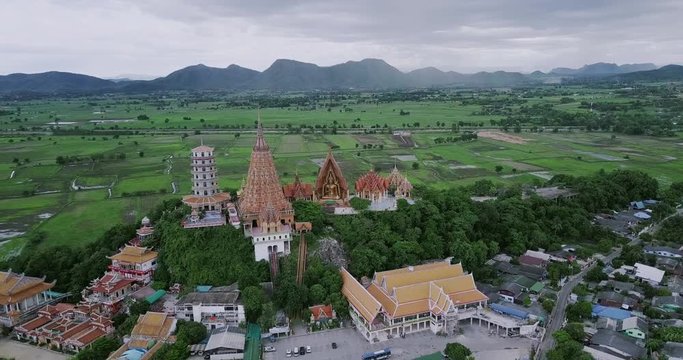Aerial view from the pagoda, golden buddha statue with rice fields and mountain background, Wat Tham Sua(Tiger Cave Temple), Tha Moung, Kanchanburi, Thailand