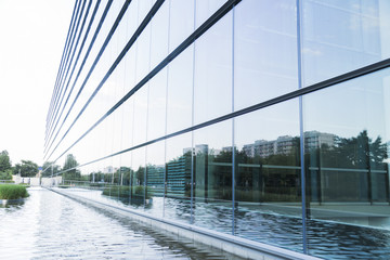 Big modern glass minimalistic office building near lake