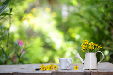 Fototapeta na wymiar Yellow flower in white pot and coffee cup on wooden table