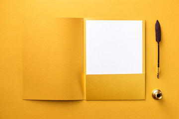 Corporate stationery set mockup. Presentation folder, letterhead and quill at golden textured paper...