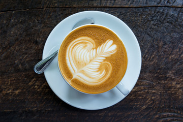 A Cup of hot latte art coffee on wooden table