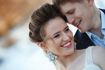Winter wedding outdoors on snow background. Bride and groom are standing and hugging.