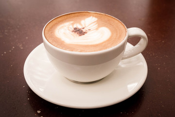  beautiful latte art with cup of hot cappuccino coffee on wooden table.