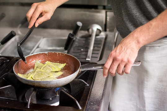 Chef stirring ravioli pasta in frying pan