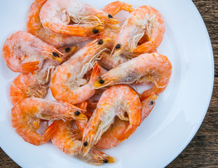 Frozen shrimp with ice cubes on a wood background