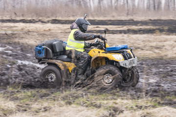 A man in a helmet on an ATV rides fast in impassable terrain