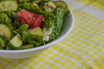 Fresh salad. Tomato, cucumber and greens in white bowl