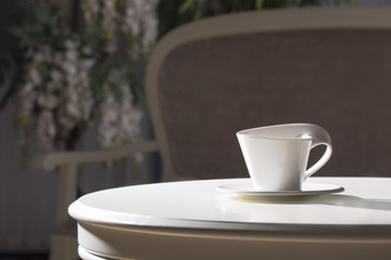 White cup and saucer. On a white table.