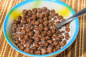 Flakes of cereals in a blue plate on a bamboo napkin
