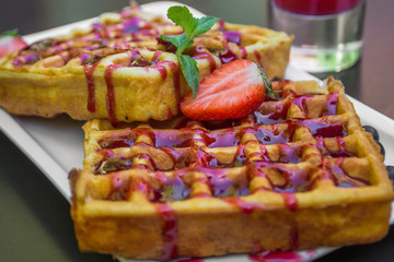 Belgium waffle topped with syrup and freshly chopped strawberries