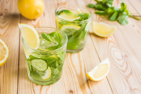 Detox water, fresh organic lemonade with ice, cucumber, lemon and mint on wooden background