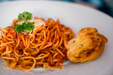 Spaghetti bolognese with a piece of rusk with garlic on a plate close up