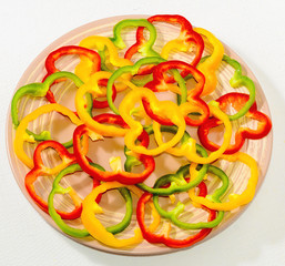 Circles of bell pepper on a ceramic plate on a white background