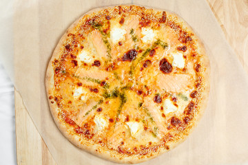 Pizza italian with salmon and feta on a paper.