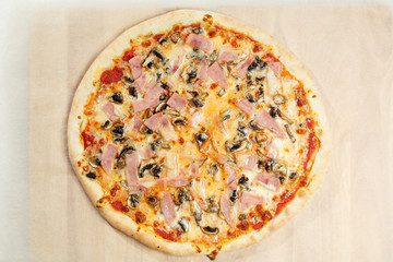 Pizza italian with ham with mushrooms on a paper.