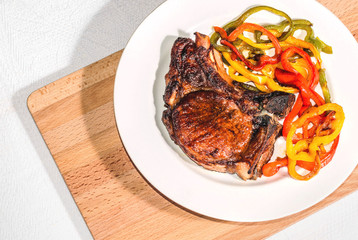 Delicious appetizing steak with vegetables on a plate on a wooden board, free, copyspace