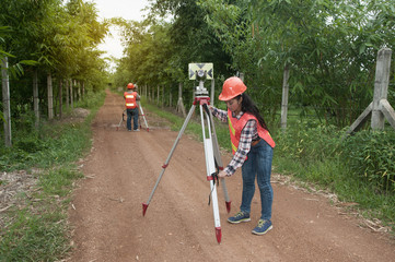 Surveyor or Engineer making measure by prism reflector with partner on the street in a field.