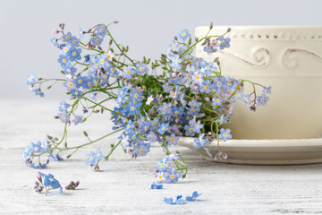 Cup of teand forget me not flowers on a wooden background