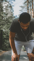 African American man preparing for a jog on a forest road. Young athletic male exercising outdoors