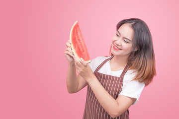 Young healthy Asian woman holds a watermelon in her hand on a pink background