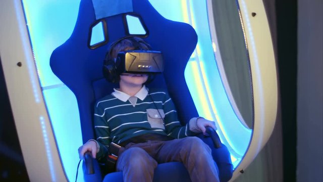 Surprised little boy experiencing virtual reality in a moving interactive chair