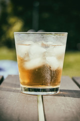 Cold drink with ice cubes on a wooden terrace table