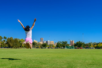Fototapeta na wymiar Happy woman jumping up in Adelaide city