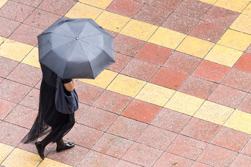 Girl with umbrella walking along paving stones