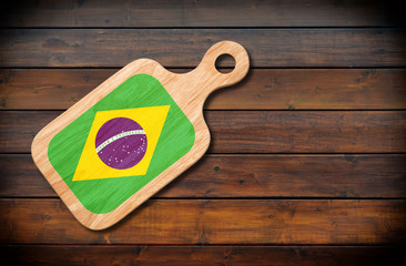 Concept of Brazilian cuisine. Cutting board with a Brazil flag on a wooden background