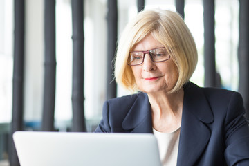 Content Senior Business Lady Working on Laptop