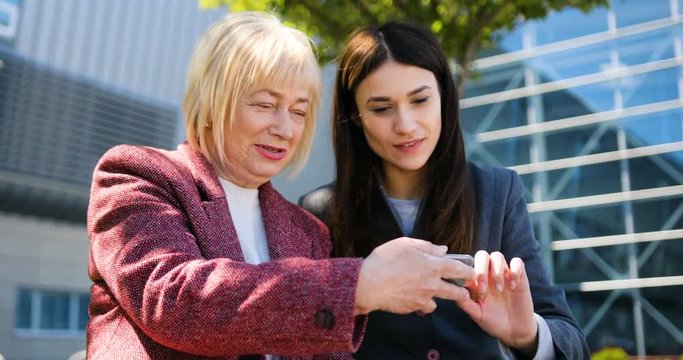 Grandmother with daughter use the phone on the street