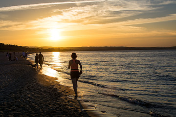 People walking and jogging along Gdansk city beach in Jelitkowo under setting sun. Gdańsk, Poland, 19.06.2017 © Agata Kowalczyk