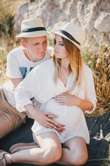 Young beautiful pregnant woman having picnic with her husband