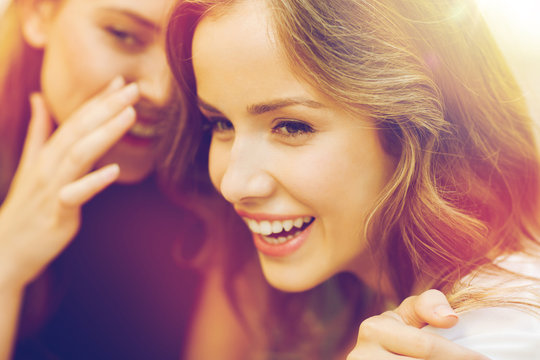 smiling young women gossiping and whispering