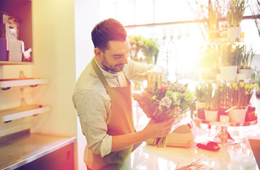 Fototapeta premium smiling florist man making bunch at flower shop