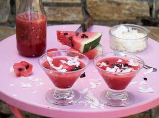Wassermelonen Smoothie auf Gartentisch vor einer Mauer