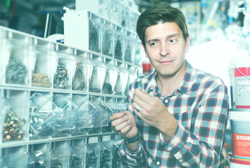 Male in hardware store choosing goods for repair