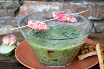 Garnelenspieß mit Gurkenkaltschale vor Gartenmauer