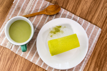 Roll cake with green tea on wooden table